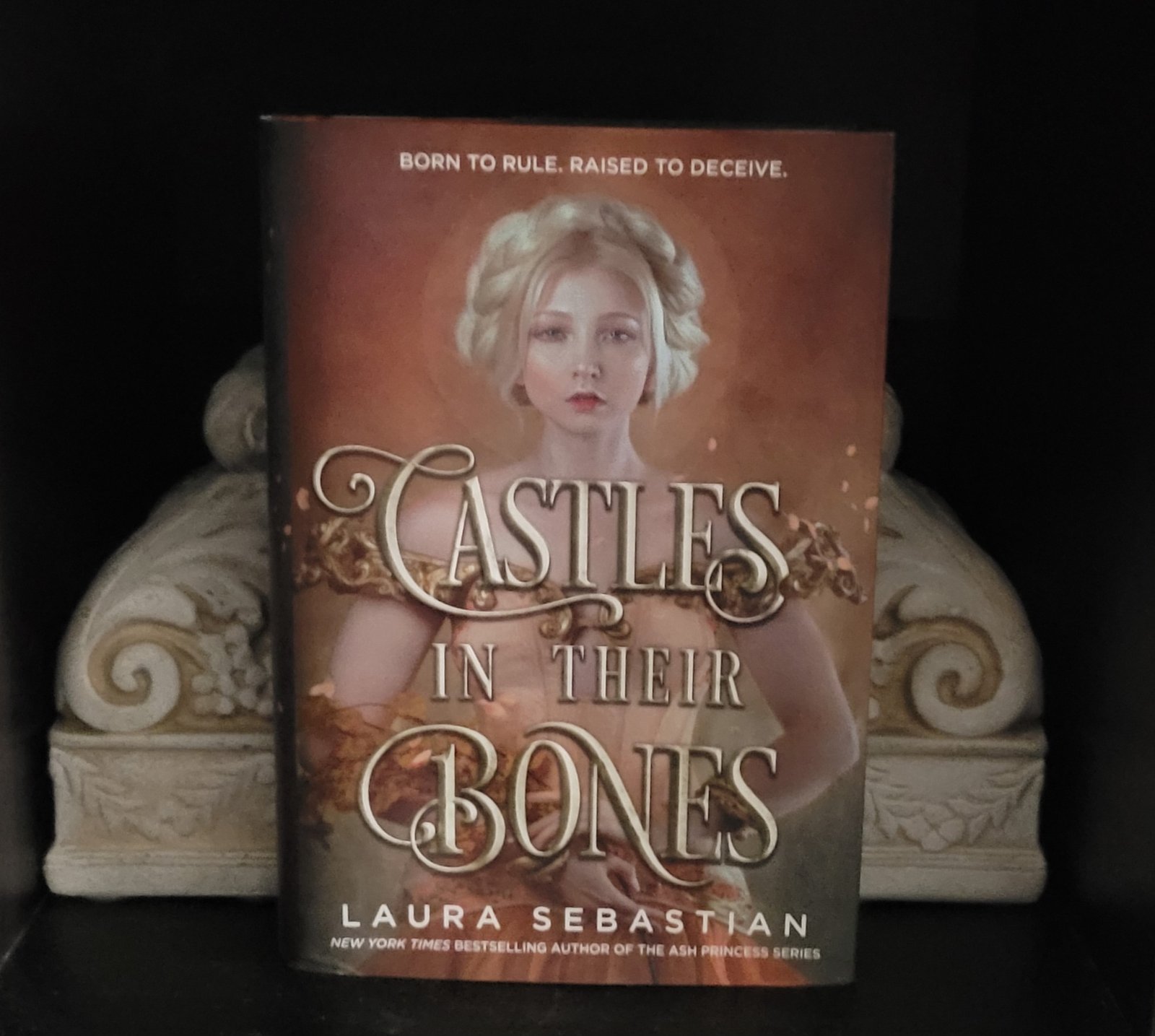 Castles in their Bones book framed by dual carved floral bookends.