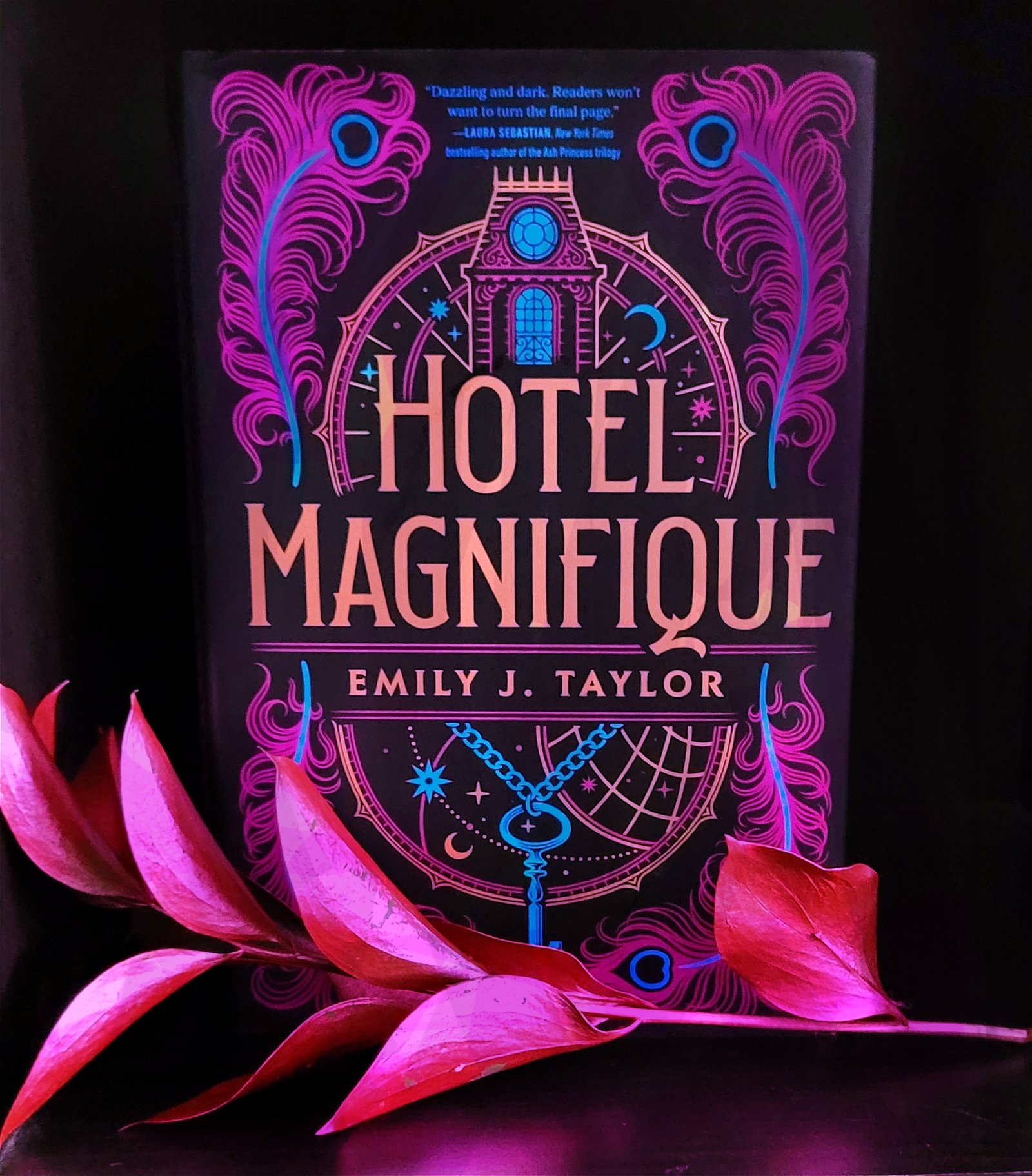 The Hotel Magnifique book, pink floral in front of it.